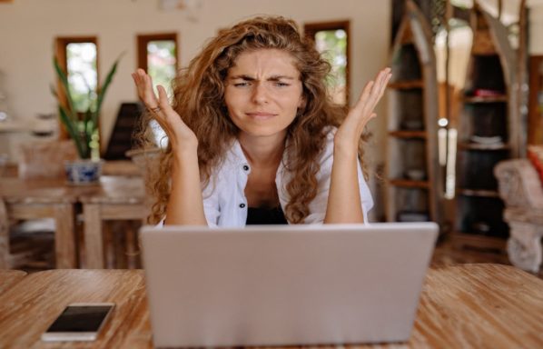 A woman looks up from a laptop computer frustrated by an email while selling a home