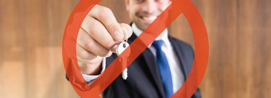 A real estate agent holds keys with a red circle with a line through it explaining how do I sell my house without an agent in Jacksonville.