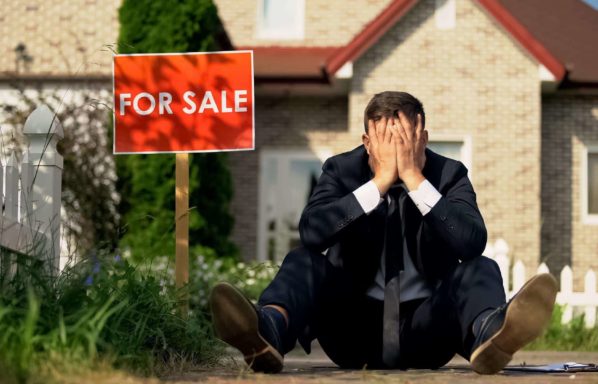 A man in a suite suite sits outside of a house with a for sale sign looking miserable. How can you move if your house hasn't sold yet in FL?