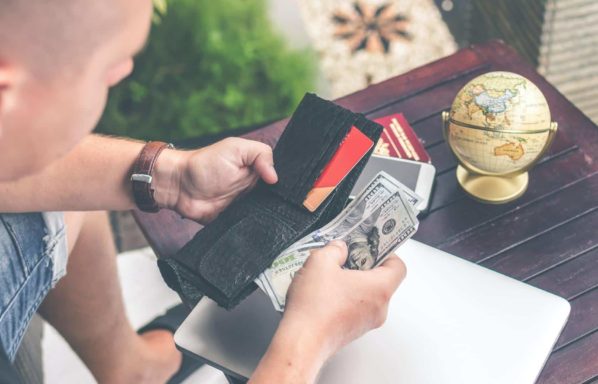 Man looks at his wallet with hundred dollar U.S. currency