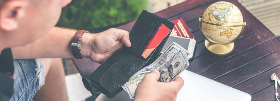 Man looks at his wallet with hundred dollar U.S. currency