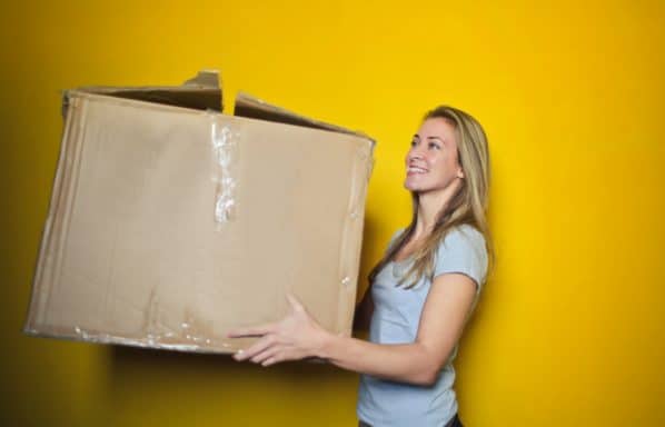 A woman holds a beat up box because she is selling her home and moving to another state