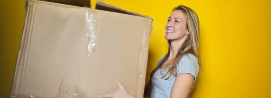 A woman holds a beat up box because she is selling her home and moving to another state