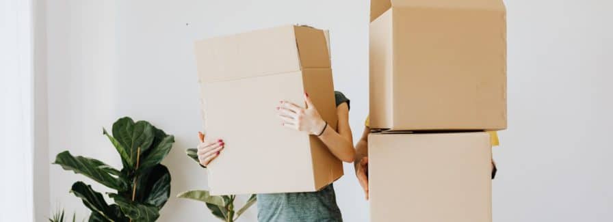 Can You sell a rental property with bad tenants? Two adults hold moving boxes in a white room of a rental home.